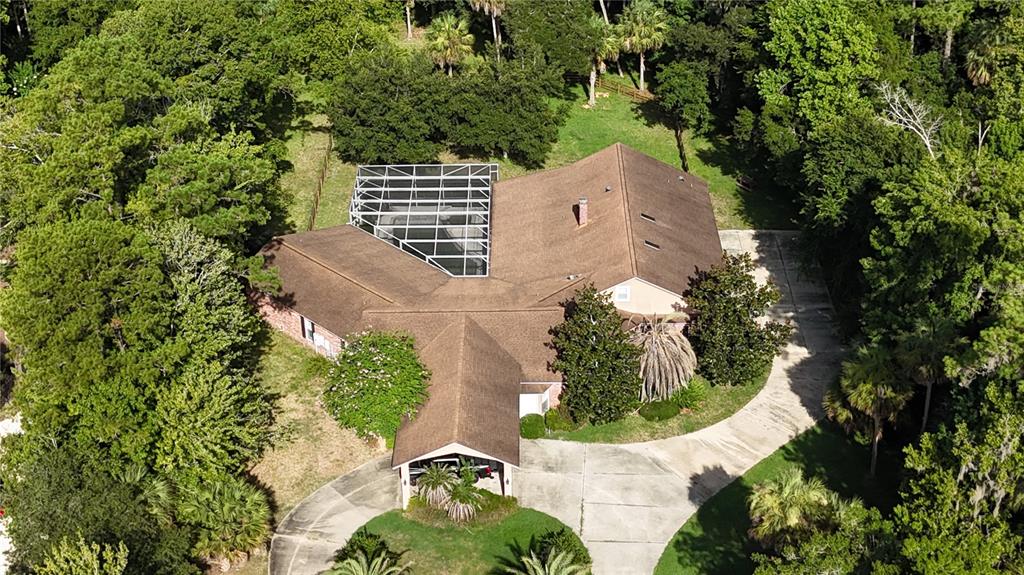 An aerial view shows a house with a brown roof, pool cage, and long driveway — 2083 BILTMORE POINT, LONGWOOD, FL