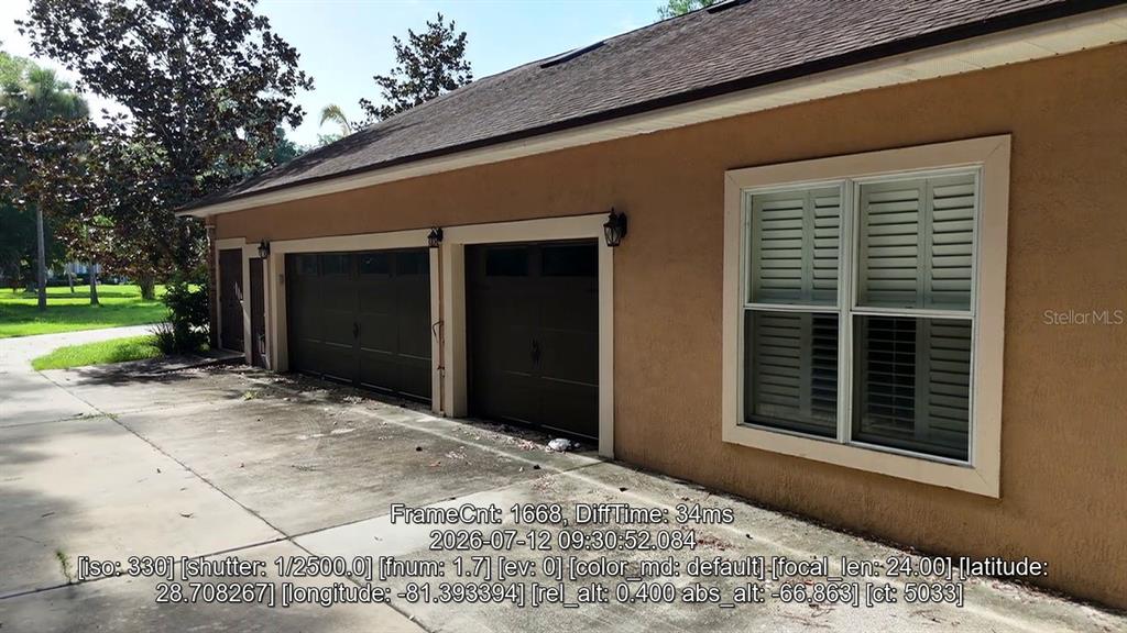 A tan house with a garage and a wooden fence sits on a grassy lot — 2083 BILTMORE POINT, LONGWOOD, FL