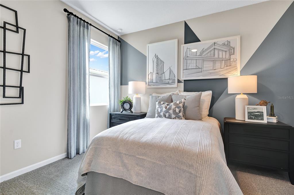 A bedroom features a bed between two nightstands, geometric wall paint, and framed architectural sketches — 180 BLUE STAR COURT, TAVARES, FL
