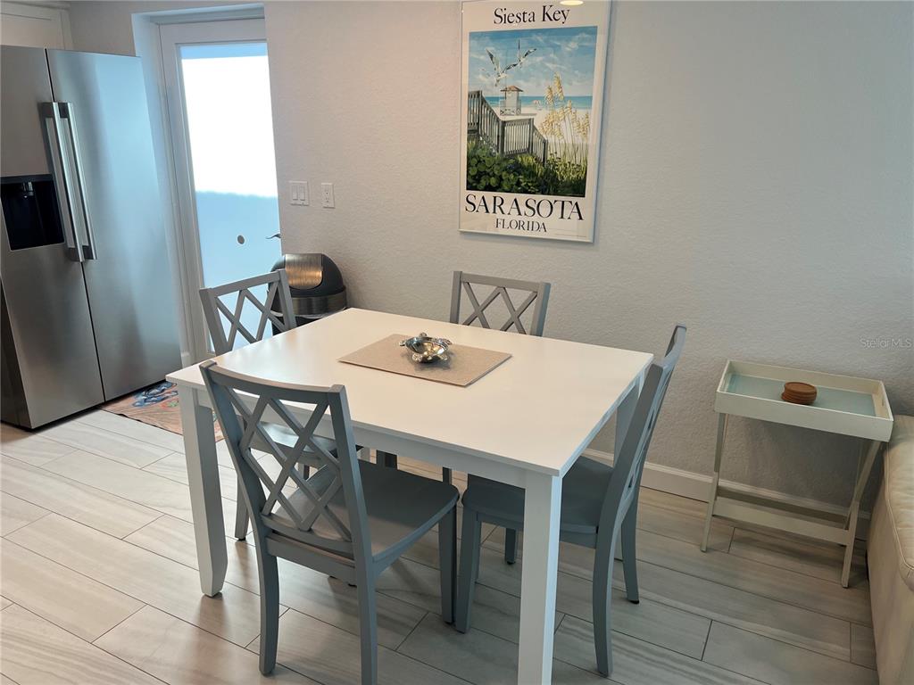 A dining area features a white table, four gray chairs, and a Siesta Key poster — 6154 MIDNIGHT PASS ROAD UNIT B02, SARASOTA, FL