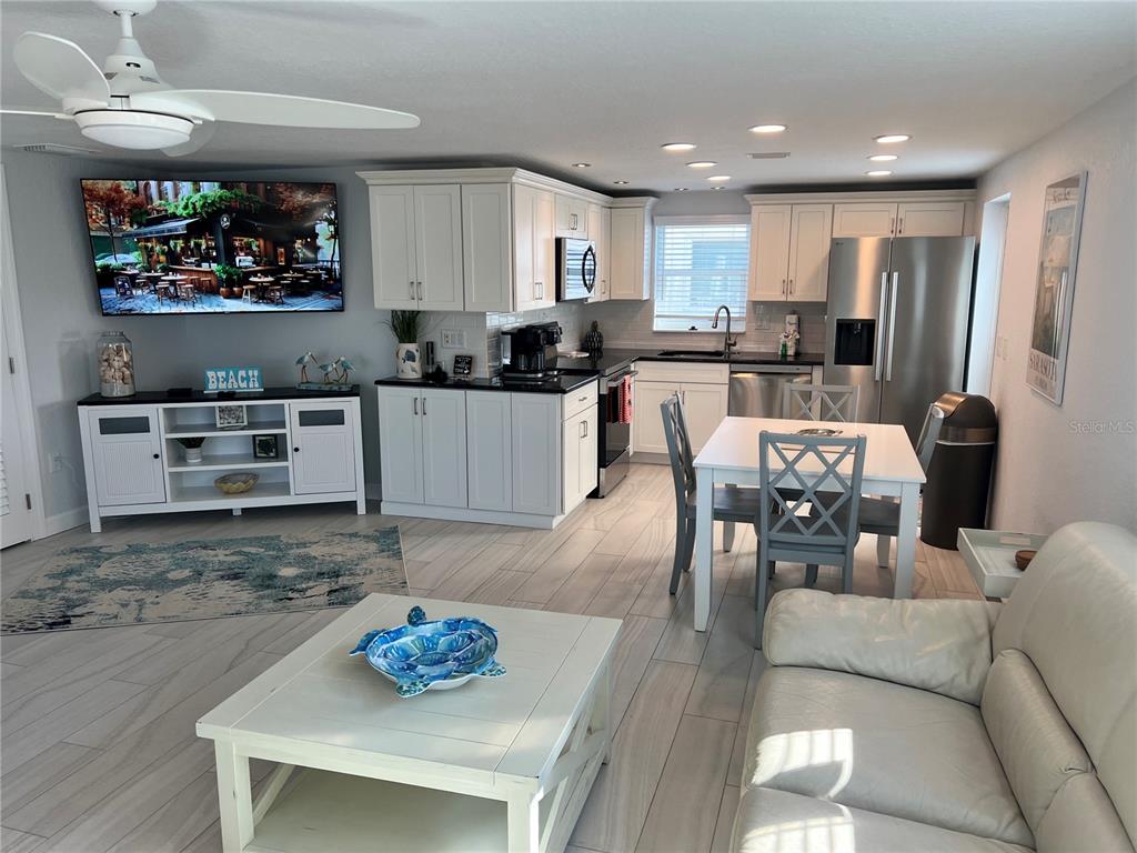 An open-concept kitchen and living area features white cabinetry, stainless steel appliances, and tile flooring — 6154 MIDNIGHT PASS ROAD UNIT B02, SARASOTA, FL