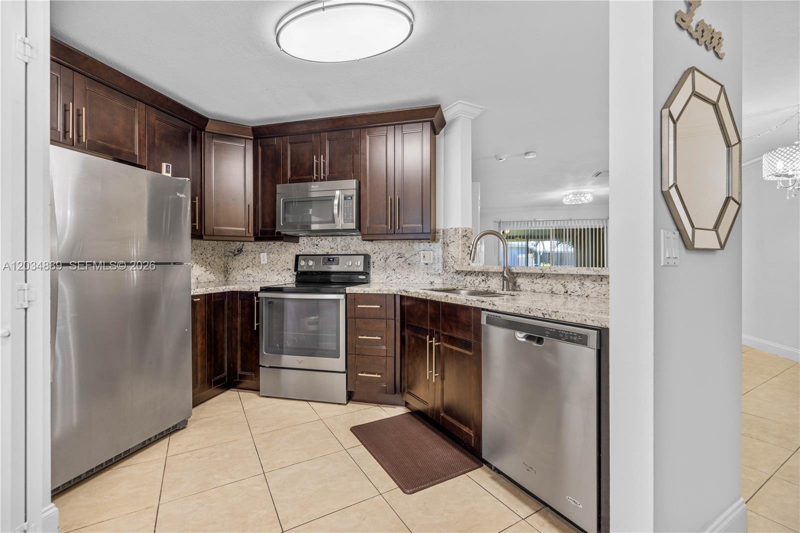 A kitchen features dark wood cabinets, stainless steel appliances, and granite countertops — 1125 SW 44th Ave, Deerfield Beach FL 33442, DEERFIELD BEACH, FL