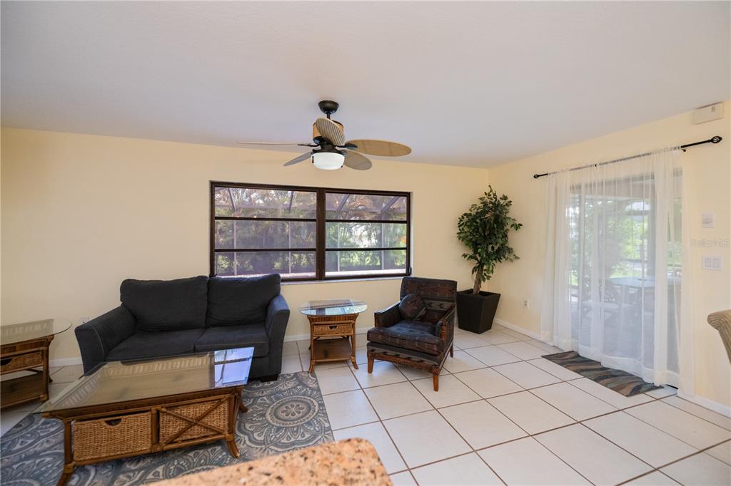 A living room features tile floors, a ceiling fan, a sofa, and a sliding glass door — 23258 MIDWAY BLVD, PORT CHARLOTTE, FL