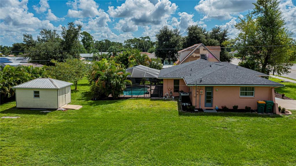 An aerial view shows a peach-colored house with a pool, screened enclosure, and detached shed — 23258 MIDWAY BLVD, PORT CHARLOTTE, FL
