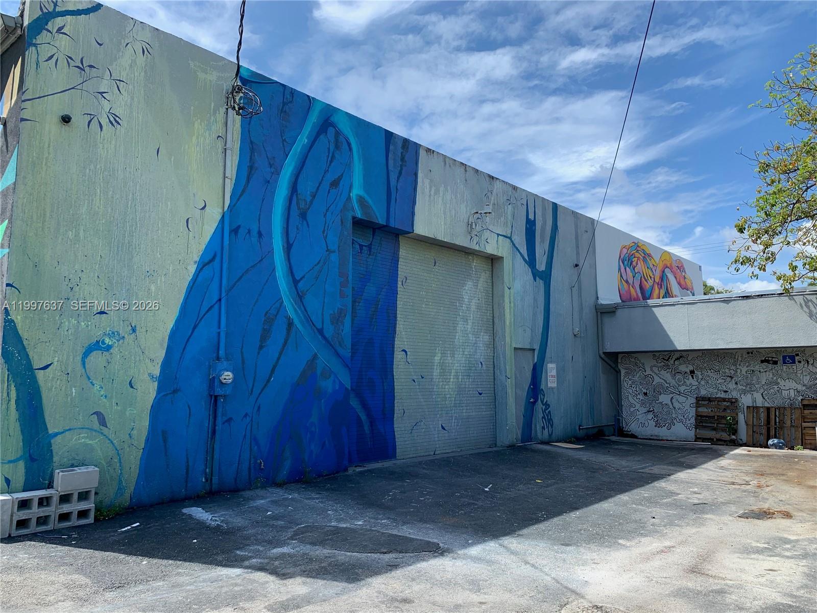 A mural-covered exterior wall of a warehouse building features a large metal roll-up door — 4151 NW 2nd Ave, Miami FL 33127, MIAMI, FL