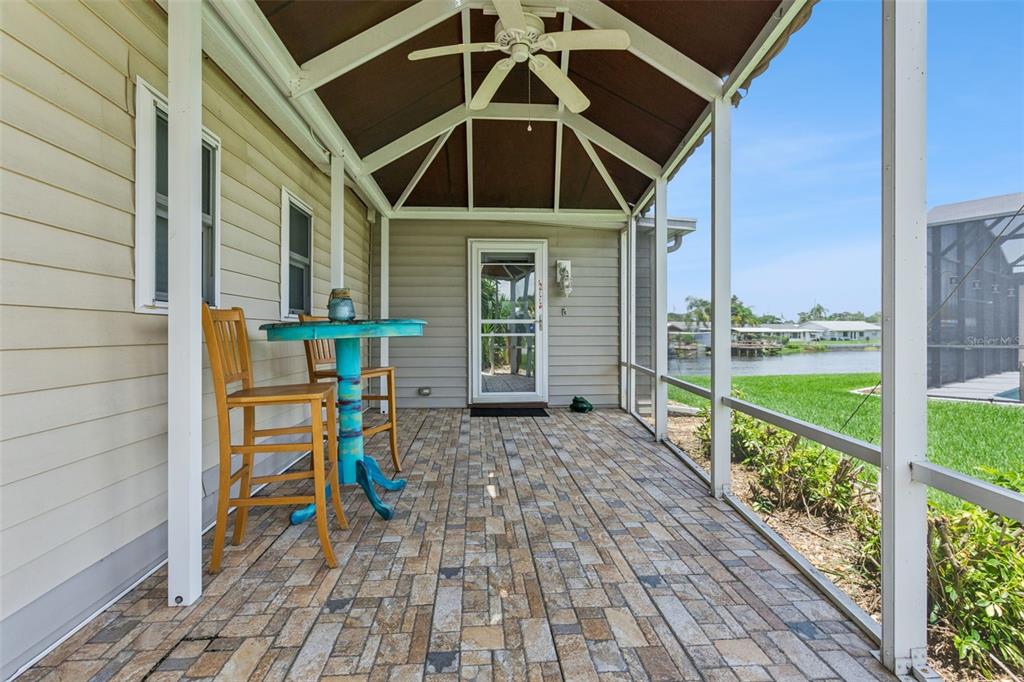 A screened-in patio with a vaulted ceiling, tiled floor, and a view of the water — 30127 GREEN BAY DRIVE, TAVARES, FL