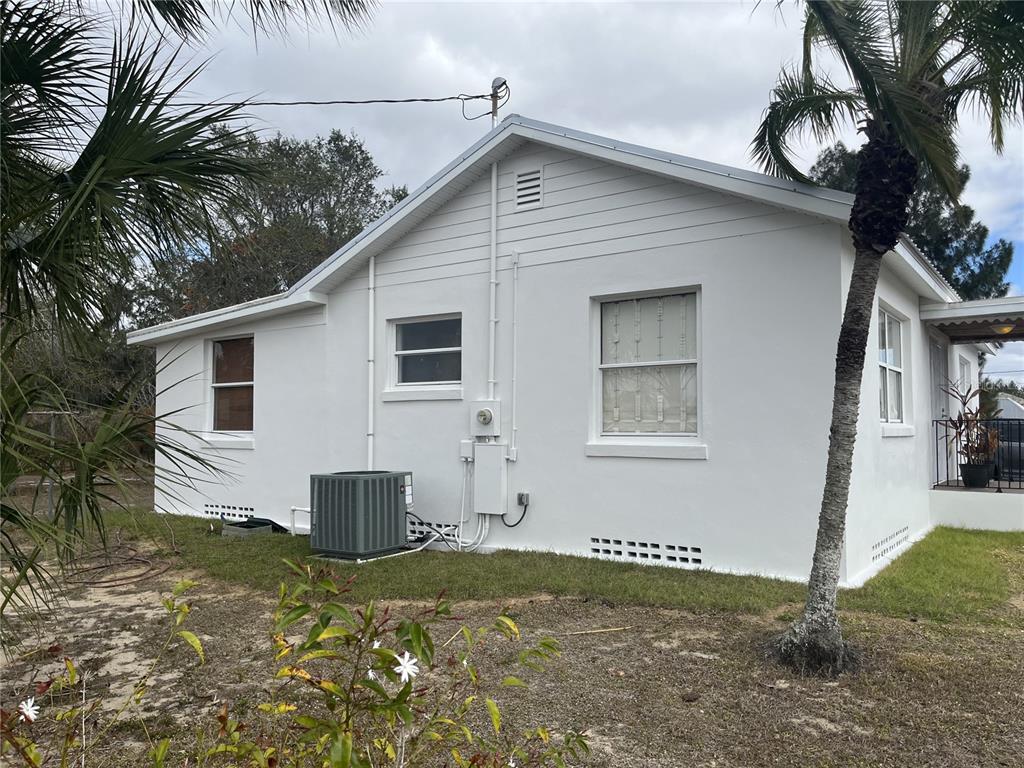 The exterior of a white house features a palm tree, an HVAC unit, and windows — 930 W MAIN STREET, AVON PARK, FL