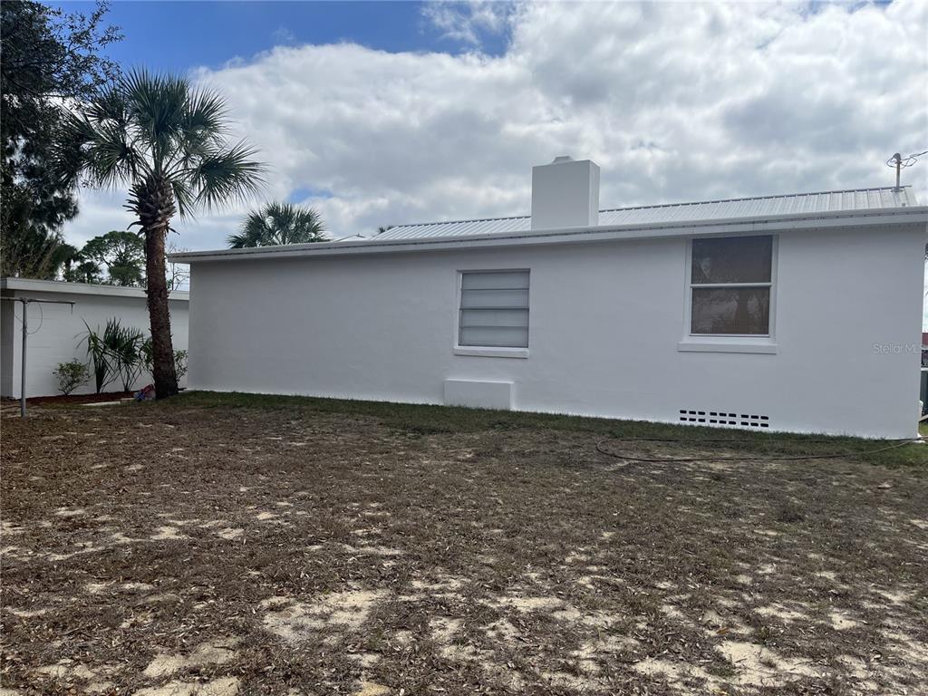 The exterior of a white house features a chimney, two windows, and a palm tree — 930 W MAIN STREET, AVON PARK, FL