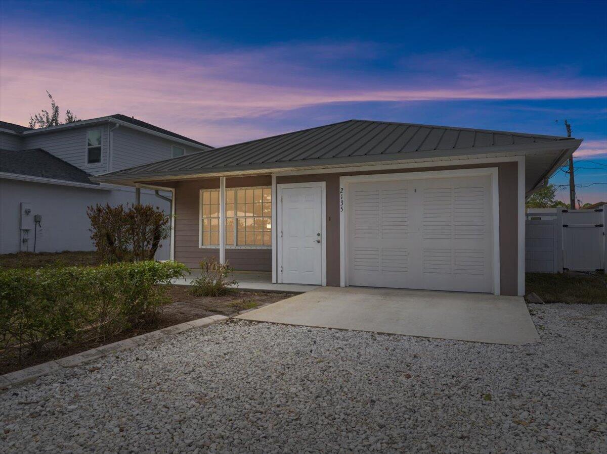 A single-story house with a metal roof, gray siding, and a gravel driveway — 2135 87th Avenue, Vero Beach FL 32966, VERO BEACH, FL