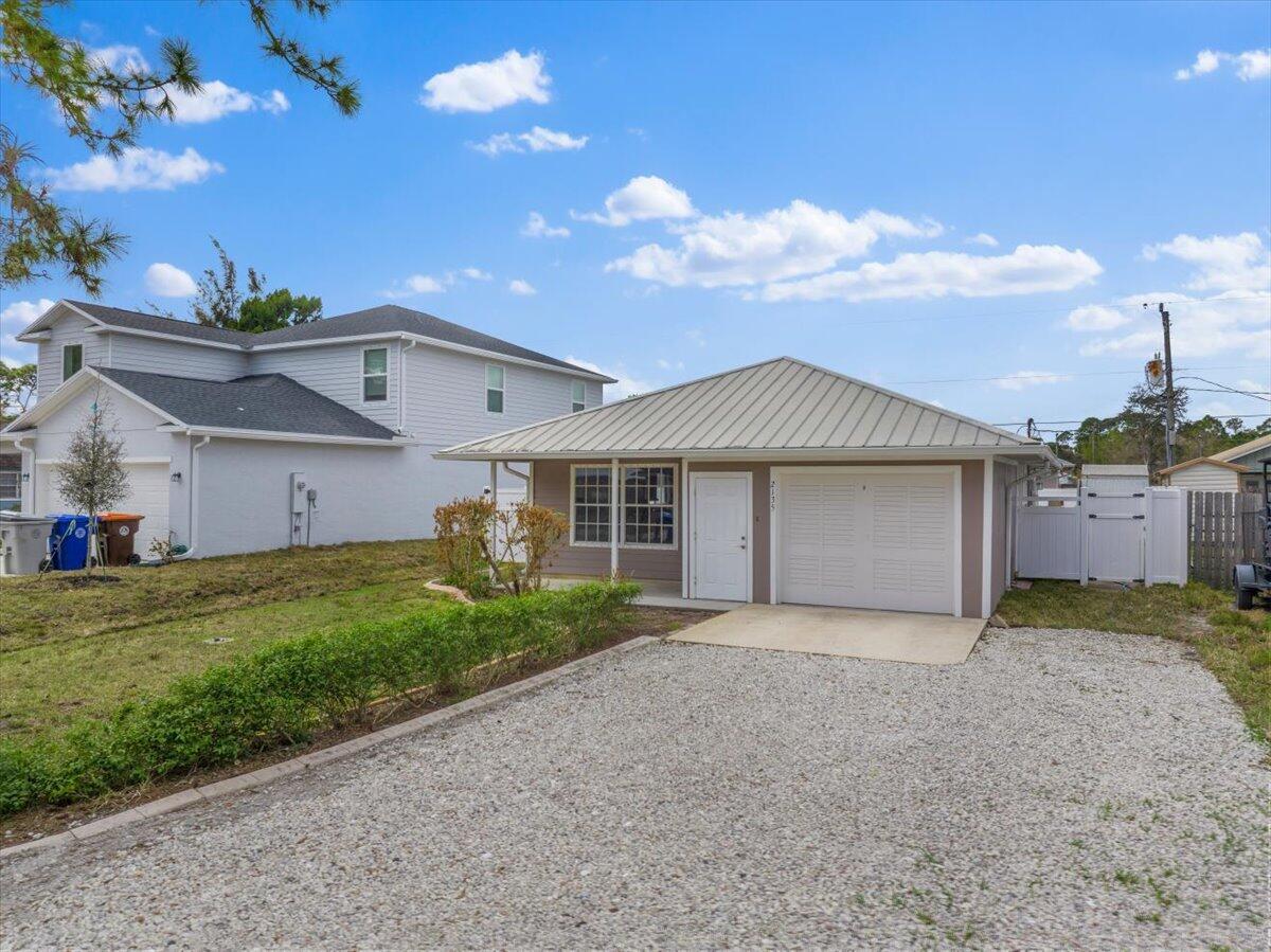 A single-story house with a metal roof, a garage, and a gravel driveway — 2135 87th Avenue, Vero Beach FL 32966, VERO BEACH, FL
