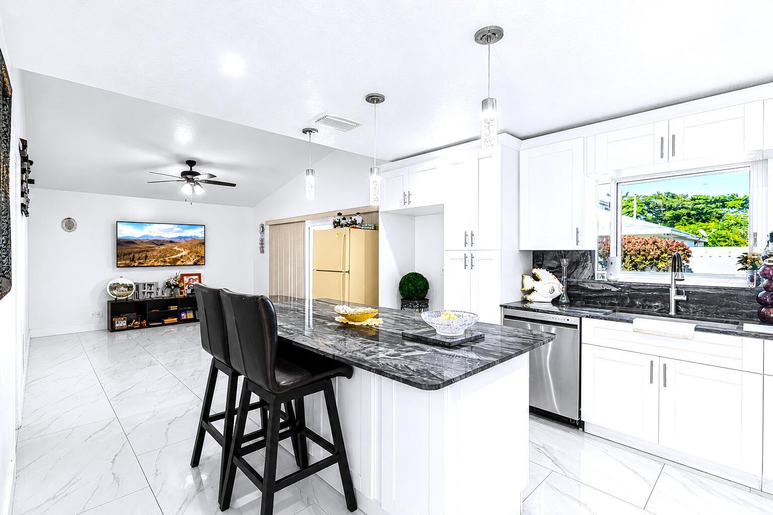 A kitchen with white cabinets, a dark marble island, and black bar stools — 3111 Thames Way, Miramar FL 33025, MIRAMAR, FL