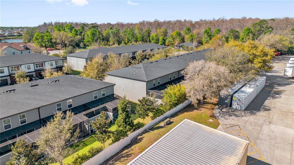 An aerial view shows several multi-story townhomes with dark roofs next to a paved lot — 4431 LE REVE COURT, KISSIMMEE, FL