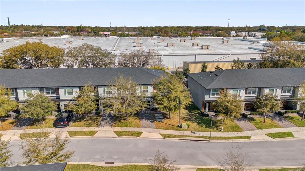 An aerial view shows two rows of townhomes with gray roofs and a large warehouse — 4431 LE REVE COURT, KISSIMMEE, FL