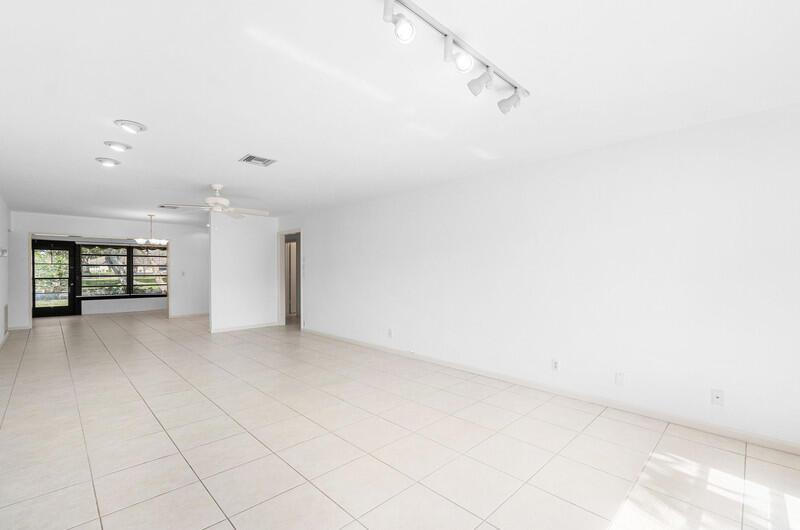 A bright, empty living room features white walls, tiled floors, and track lighting — 10120 Eaglewood Terrace # B, Boynton Beach FL 33436, BOYNTON BEACH, FL