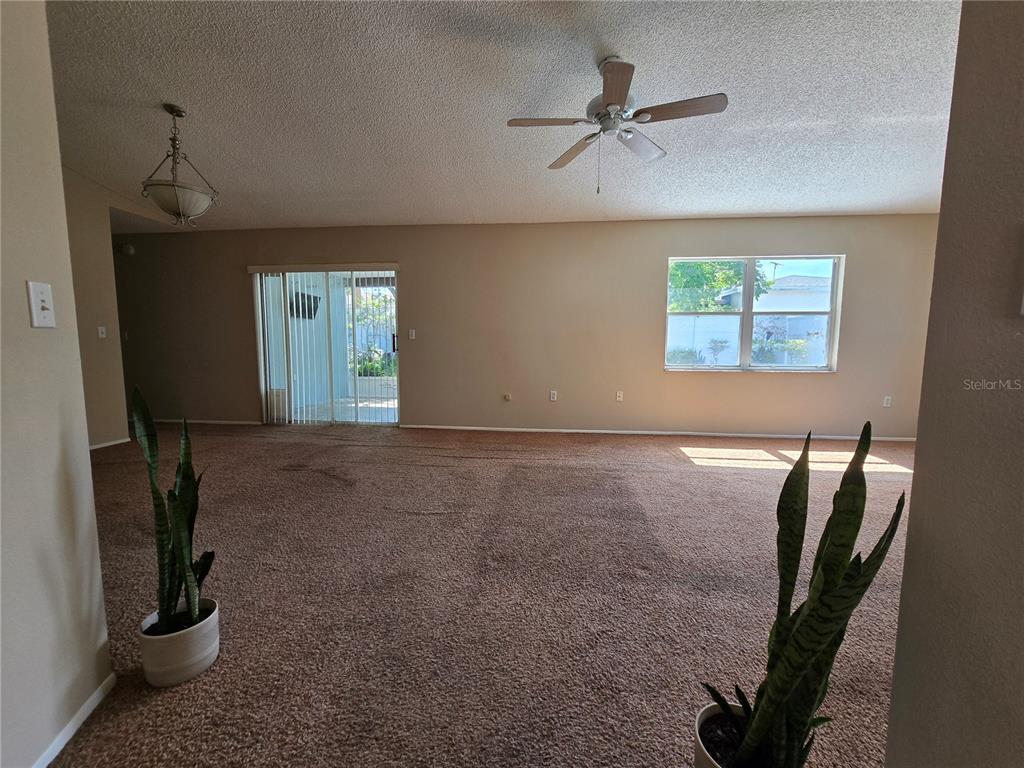 A carpeted hallway leads into a living room with a ceiling fan and sliding doors — 9836 MOREHEAD LANE, PORT RICHEY, FL