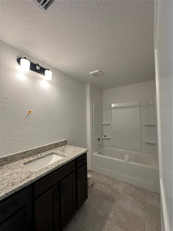 A bathroom features a dark wood vanity with a granite countertop and a tub-shower combo — 12555 NE 48TH TERR, OXFORD, FL