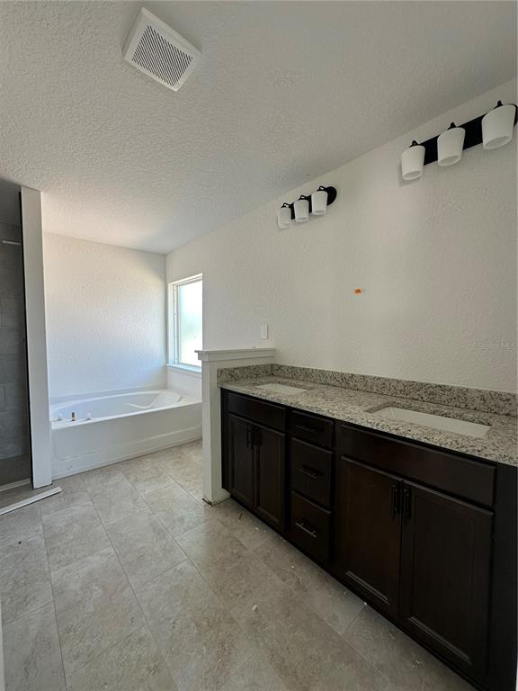 A bathroom features a double vanity with dark cabinets, granite countertops, and a soaking tub — 12555 NE 48TH TERR, OXFORD, FL