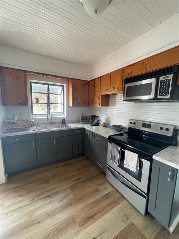 A kitchen features gray lower cabinets, natural wood upper cabinets, and stainless steel appliances — 4416 123RD ST COURT W, CORTEZ, FL