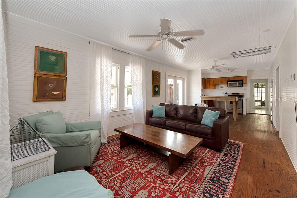 A living room features white beadboard walls, a red patterned rug, and a brown sofa — 4416 123RD ST COURT W, CORTEZ, FL