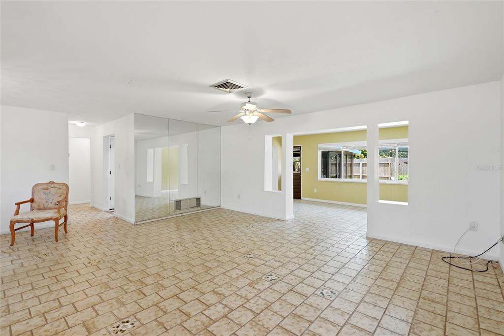 A living room features tiled floors, a mirrored wall, and an opening to another room — 2711 GULF GATE DRIVE, SARASOTA, FL