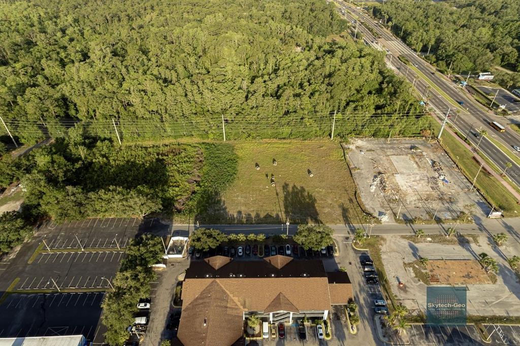 An aerial view shows a vacant lot situated between a wooded area and a commercial building — 4200 W VINE STREET, KISSIMMEE, FL