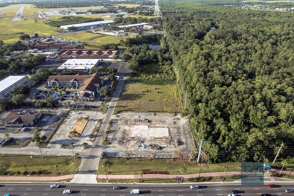 An aerial view shows a vacant lot with a concrete foundation next to a forest — 4200 W VINE STREET, KISSIMMEE, FL