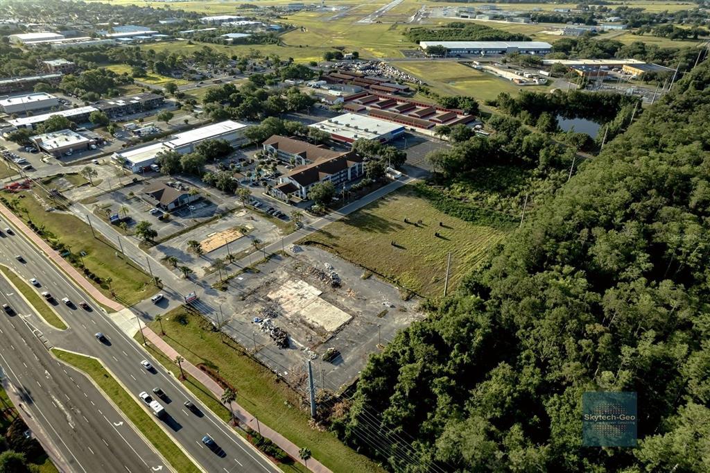 An aerial view shows a commercial lot with a concrete foundation next to a highway — 4200 W VINE STREET, KISSIMMEE, FL