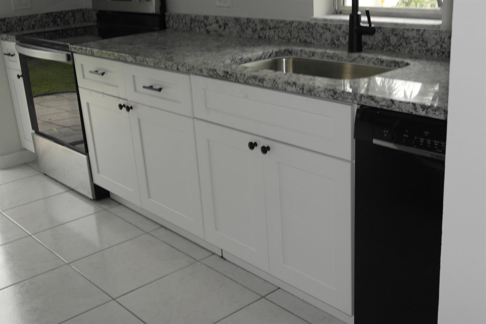 A kitchen features white shaker cabinets, granite countertops, a stainless steel stove, and a dishwasher — 18890 Candlewick Drive # B, Boca Raton FL 33496, BOCA RATON, FL