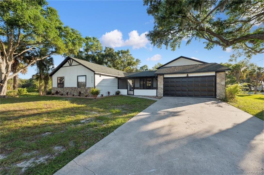 A single-story house with white siding, stone accents, and a dark garage door — 2195 N SLEWFOOT PATH, CRYSTAL RIVER, FL