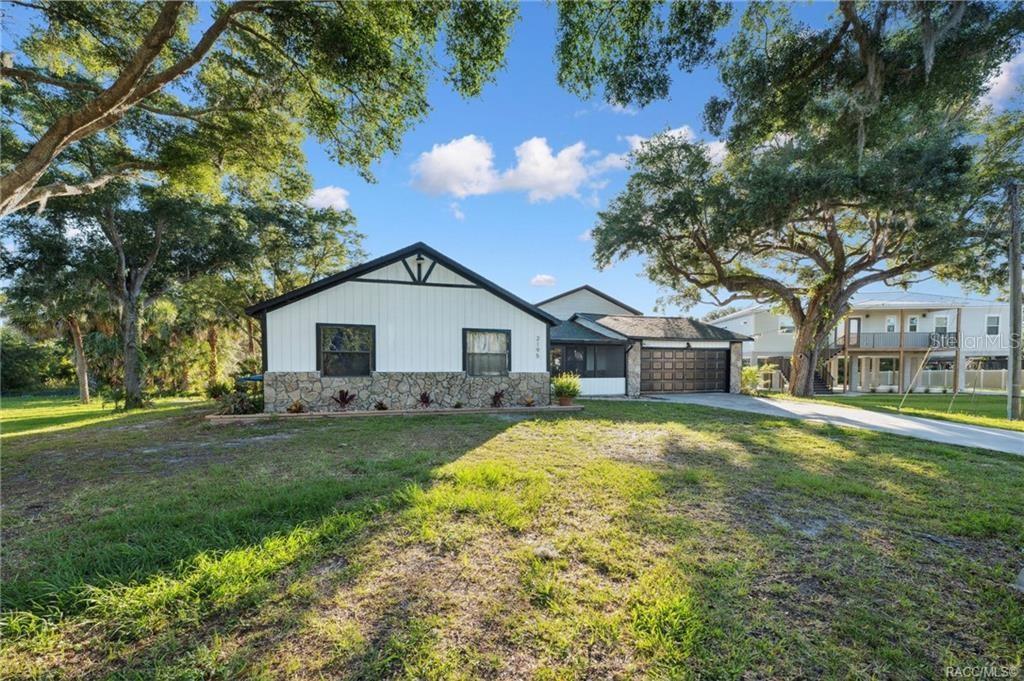 A single-story house with a stone facade, white siding, and a dark-trimmed gable roof — 2195 N SLEWFOOT PATH, CRYSTAL RIVER, FL