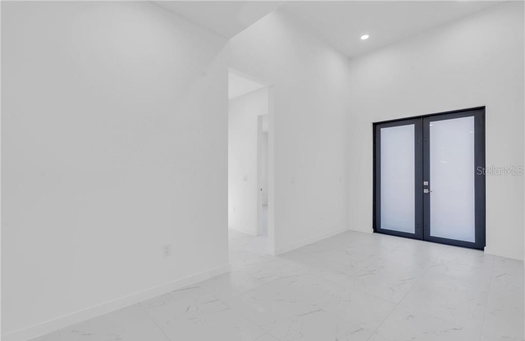 A bright room with white marble-look tile floors and black-framed double glass doors — 3101 NW 42ND PLACE, CAPE CORAL, FL