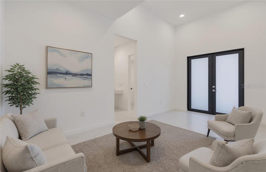 A bright living room features white walls, a vaulted ceiling, and modern furniture on carpet — 3101 NW 42ND PLACE, CAPE CORAL, FL