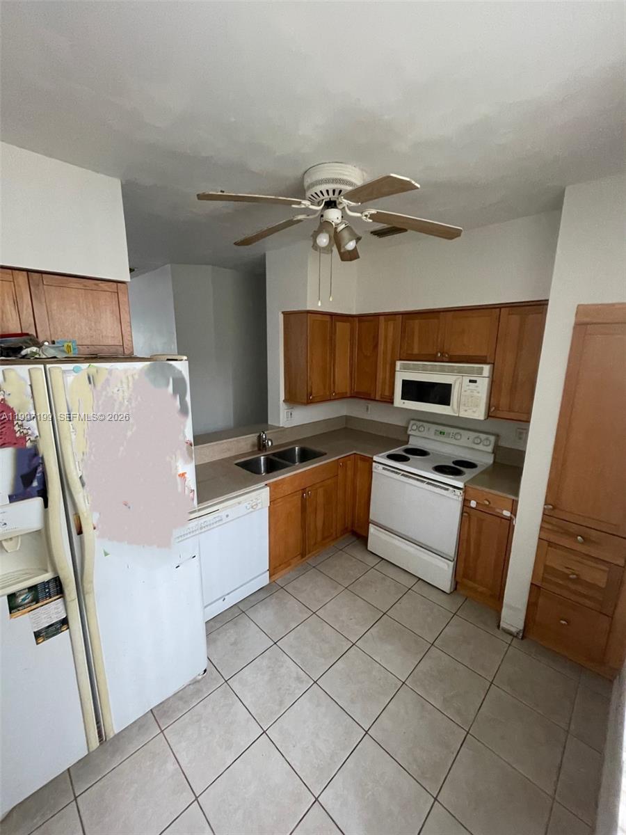 A kitchen features wood cabinets, white appliances, a double sink, and light-colored tile flooring — 870 NE 212th Ter # 3, Miami FL 33179, MIAMI, FL
