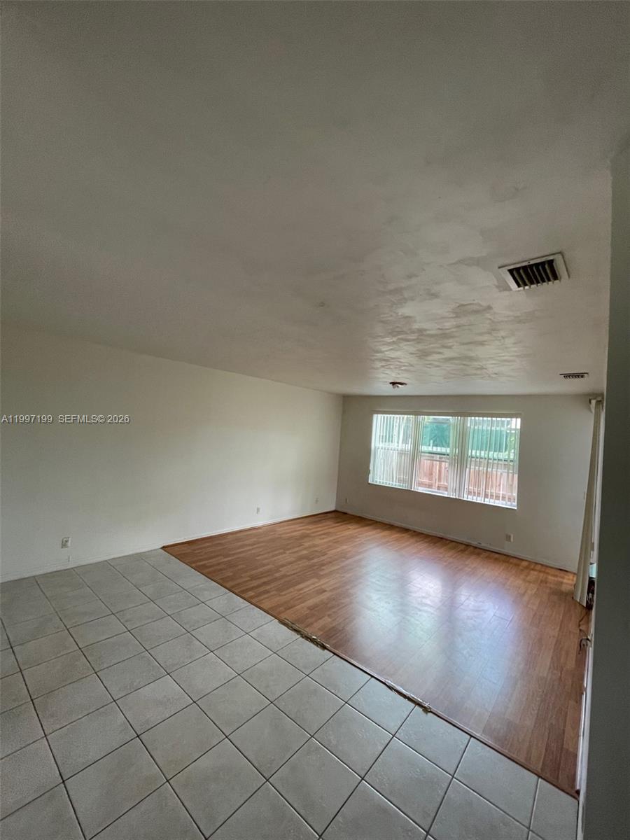 This room features a combination of light-colored floor tiles and wood-look laminate flooring — 870 NE 212th Ter # 3, Miami FL 33179, MIAMI, FL