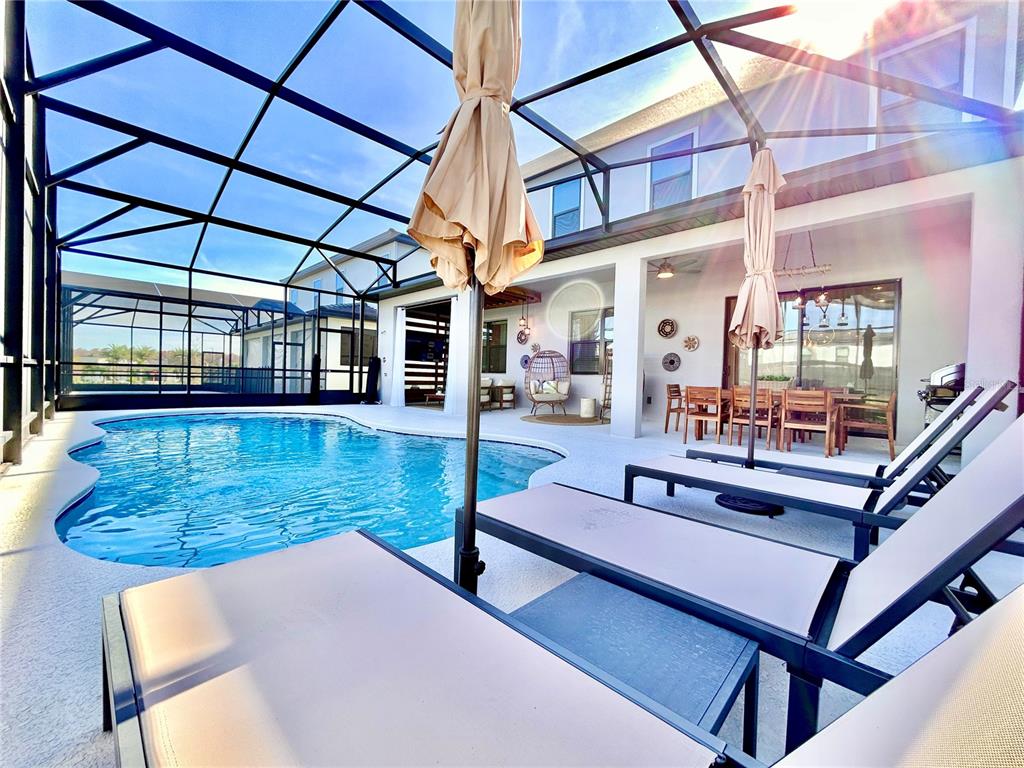 A screened-in patio features a swimming pool, lounge chairs, and an outdoor dining area — 6271 SAND SKIPPER ROAD, ORLANDO, FL