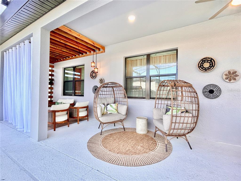 A covered patio features two wicker egg chairs, a round rug, and wall-mounted decorative baskets — 6271 SAND SKIPPER ROAD, ORLANDO, FL
