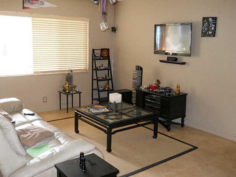 A living room features a white leather sofa, a glass-topped coffee table, and a wall-mounted television — 520 SW 15th Street # 101, Pompano Beach FL 33060, POMPANO BEACH, FL