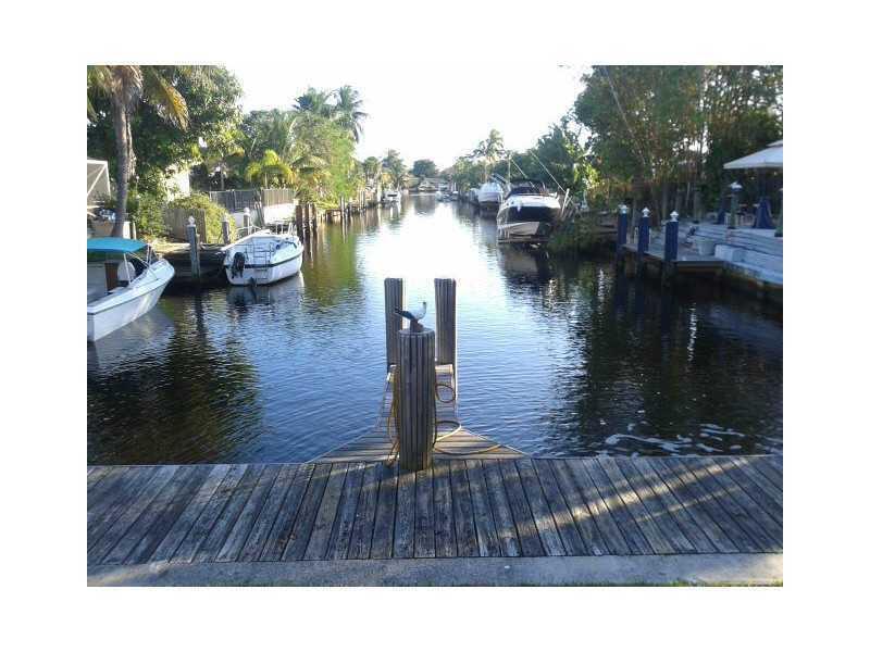 A wooden dock extends into a narrow canal lined with boats and tropical vegetation — 520 SW 15th Street # 101, Pompano Beach FL 33060, POMPANO BEACH, FL