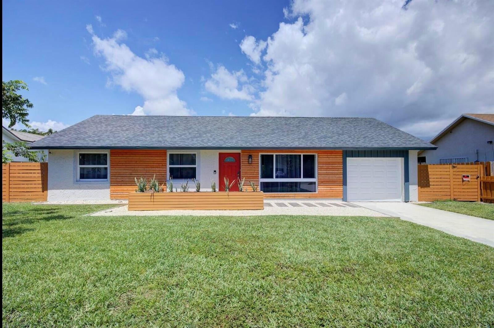 A single-story house with wood siding, a red front door, and a front lawn — 3026 Dunlin Road, Delray Beach FL 33444, DELRAY BEACH, FL