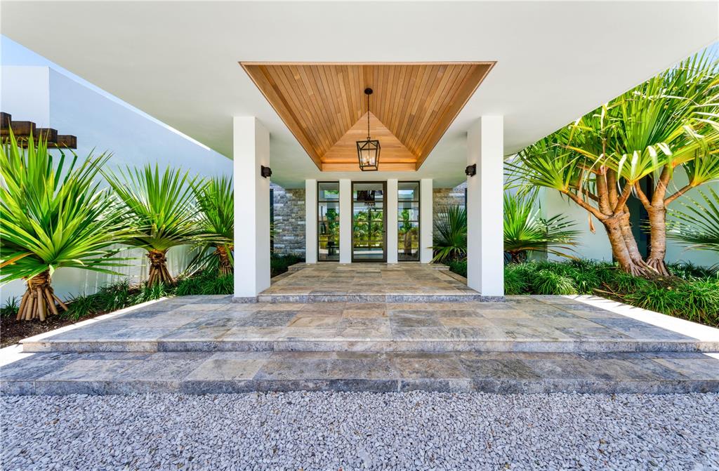 A modern home entrance features a stone-tiled porch, wood-paneled ceiling, and tropical landscaping — 7000 BAHIA BEACH BLVD., 23 LAS ESTANCIAS, RIO GRANDE, PR