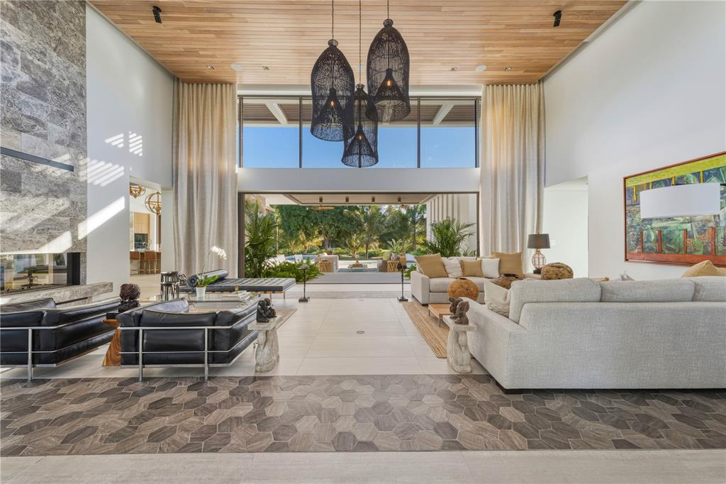 A spacious living room features high wood-paneled ceilings, large pendant lights, and floor-to-ceiling windows — 7000 BAHIA BEACH BLVD., 23 LAS ESTANCIAS, RIO GRANDE, PR