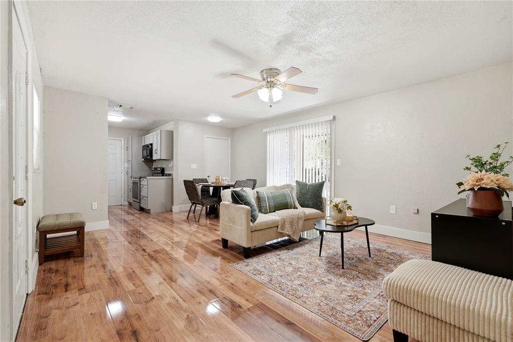 A living room with wood-look flooring, a ceiling fan, and an adjacent dining area and kitchen — 1823 NE 31ST AVENUE, GAINESVILLE, FL