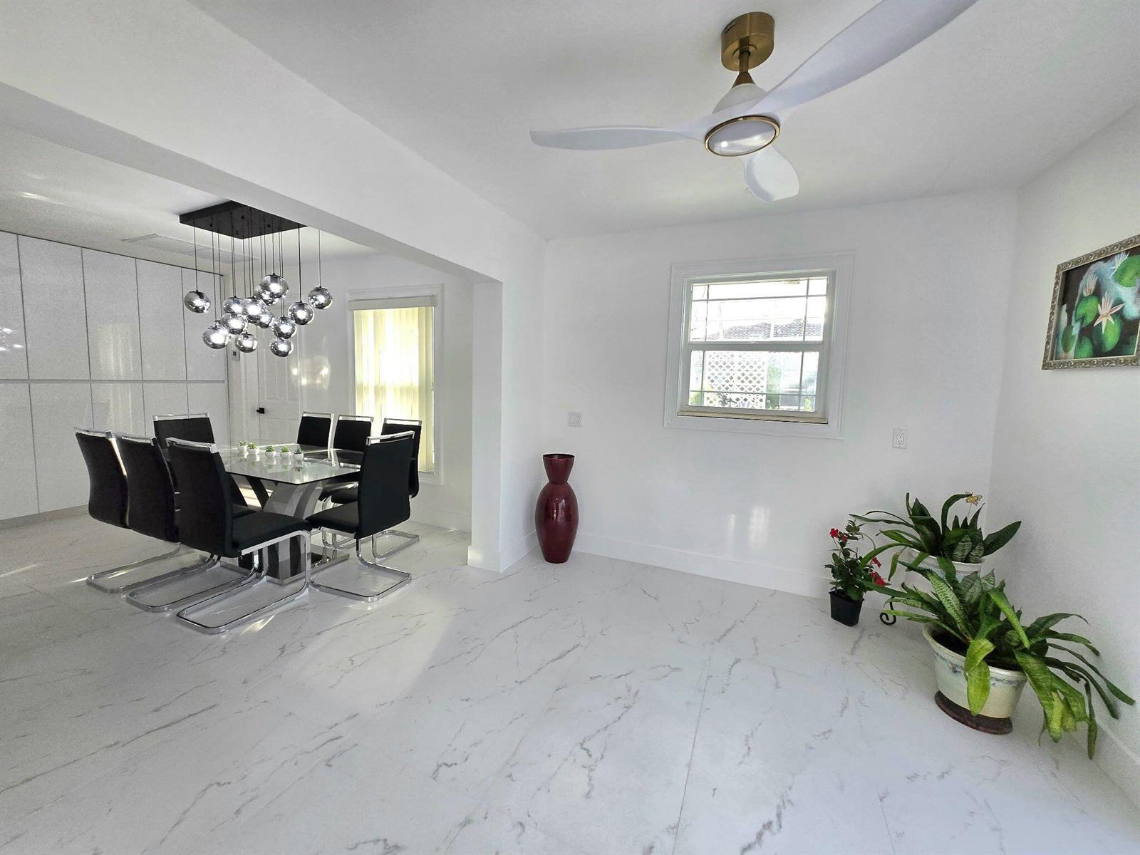A dining room with white marble-look floors, a modern chandelier, and a ceiling fan — 12231 Areaca Drive, Wellington FL 33414, WELLINGTON, FL