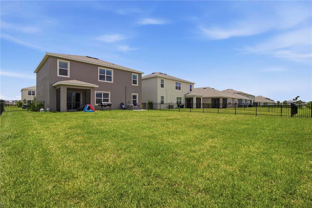 The rear exterior of two-story houses features fenced backyards and covered patios under a blue sky — 18114 WHEATHOUSE PLACE, BRADENTON, FL