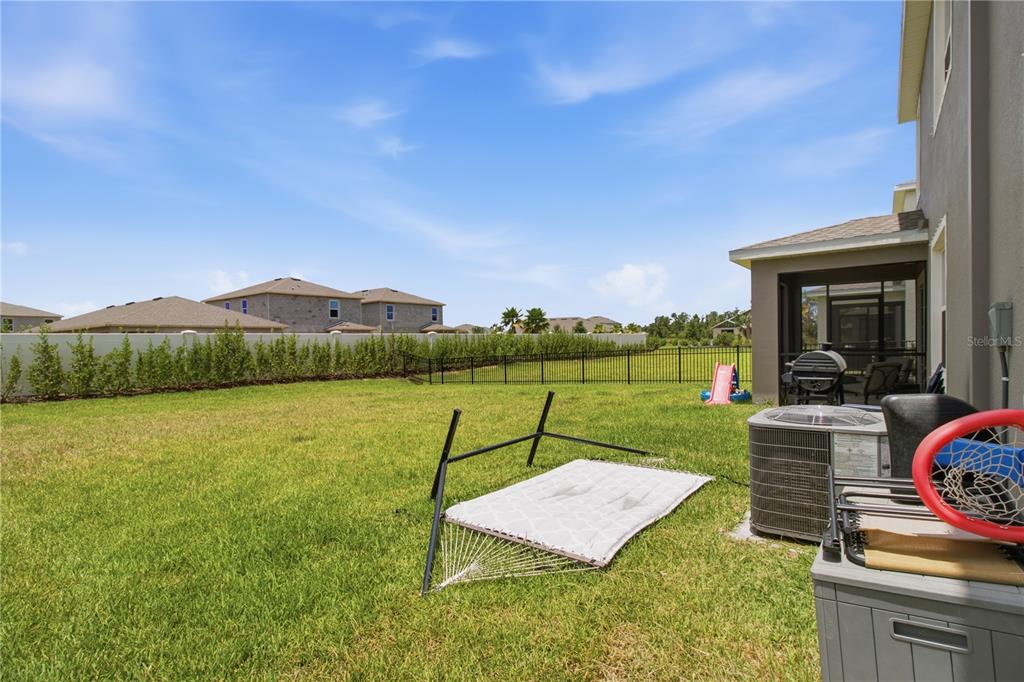 A backyard features a hammock, a patio, a fence, and a view of neighboring houses — 18114 WHEATHOUSE PLACE, BRADENTON, FL