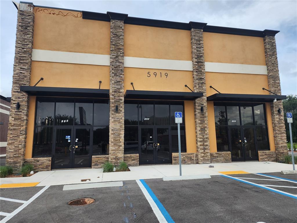 A commercial building exterior features tan stucco walls, stone pillars, and three glass entry doors — 5919 S ORANGE BLOSSOM TRAIL TRAIL UNIT 110, ORLANDO, FL