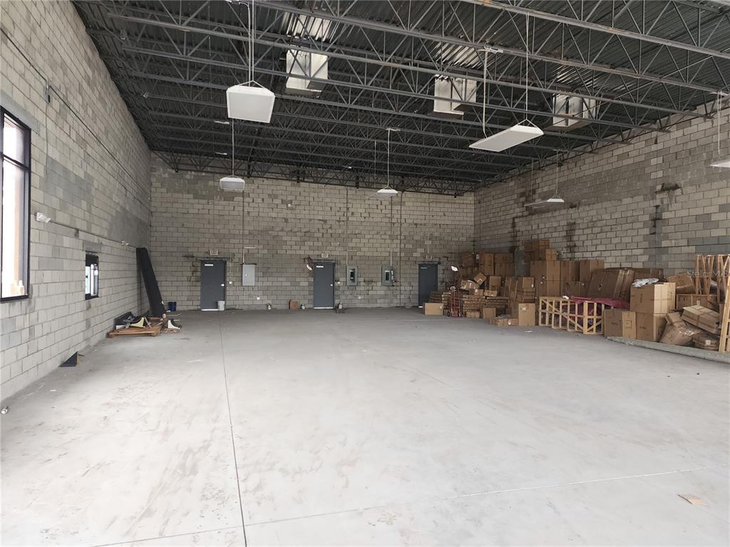 An industrial warehouse space features concrete block walls, a high open-truss ceiling, and concrete flooring — 5919 S ORANGE BLOSSOM TRAIL TRAIL UNIT 110, ORLANDO, FL