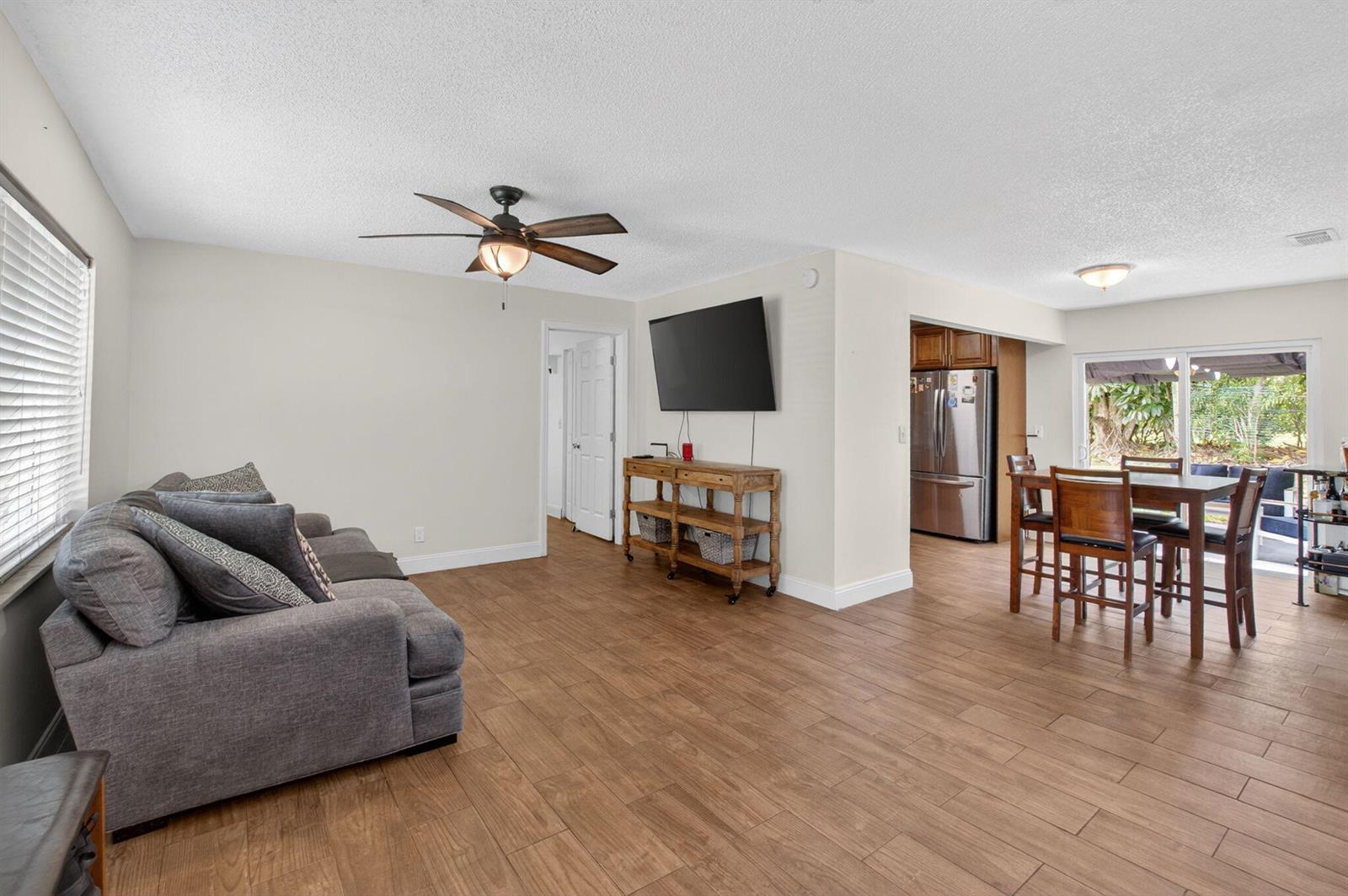 A living room with wood-look tile flooring, a gray sofa, and an adjacent dining area — 9734 Alaska Circle, Boca Raton FL 33434, BOCA RATON, FL