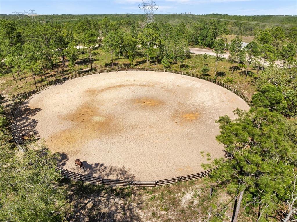 An aerial view of a circular horse training ring with a sand surface and wooden fencing — 25723 BAREVA ROAD, WEEKI WACHEE, FL