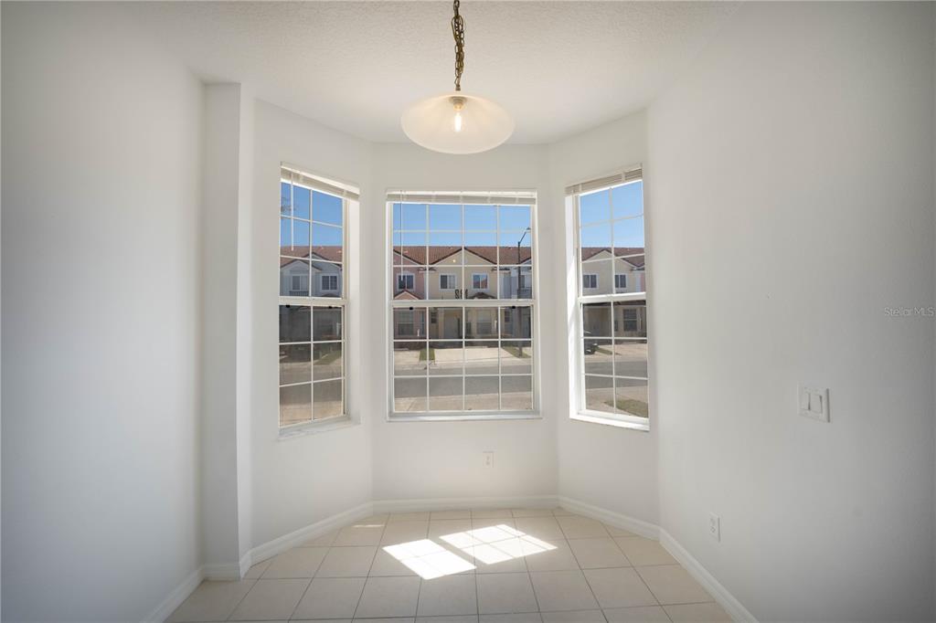 A bright breakfast nook features tile flooring, a pendant light, and three large bay windows — 1241 S BEACH CIRCLE, KISSIMMEE, FL